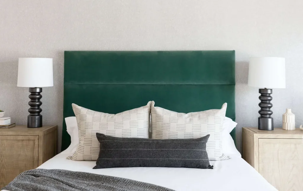 Modern bedroom with emerald green upholstered headboard and neutral bedding