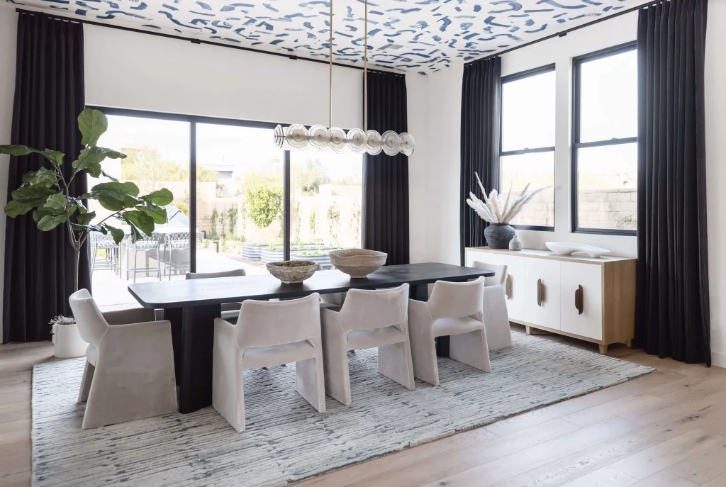 Dining room with black table, sculptural chairs, and patterned ceiling