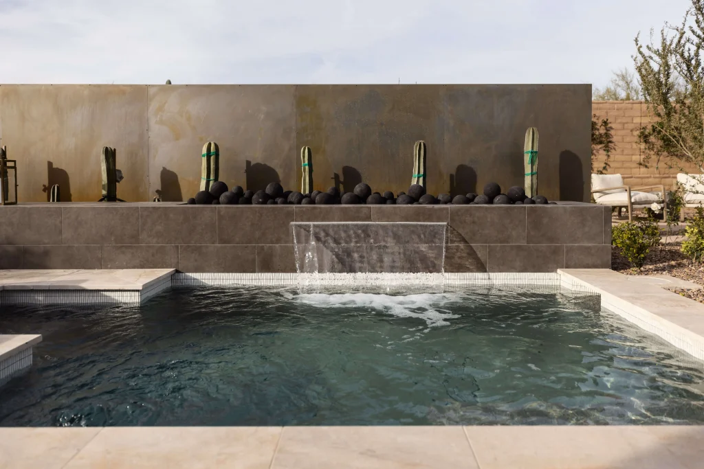 Backyard pool with waterfall and decorative cactus feature wall