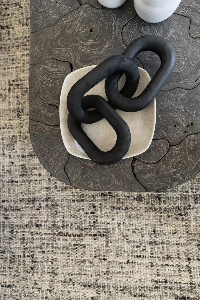 Sculptural decor on a rustic wooden surface with a woven rug underneath