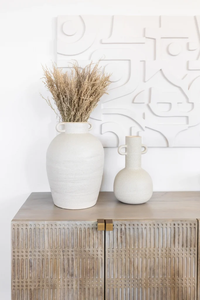 Neutral ceramic vases on a textured wood cabinet