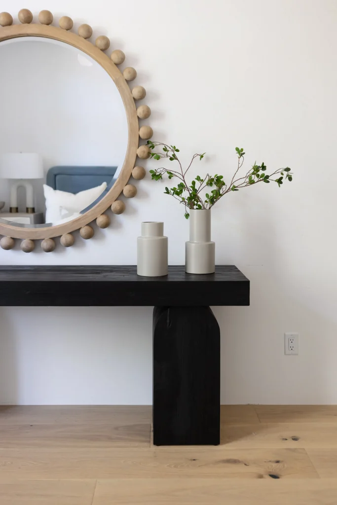 Round mirror above black console with minimalist decor