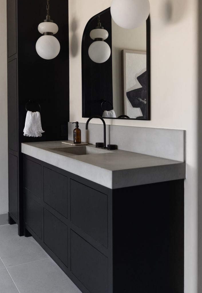 A black vanity with a concrete countertop, rectangular sink, black faucet, wall mirror, pendant lights, and a white towel on a ring. — Living with Lolo.
