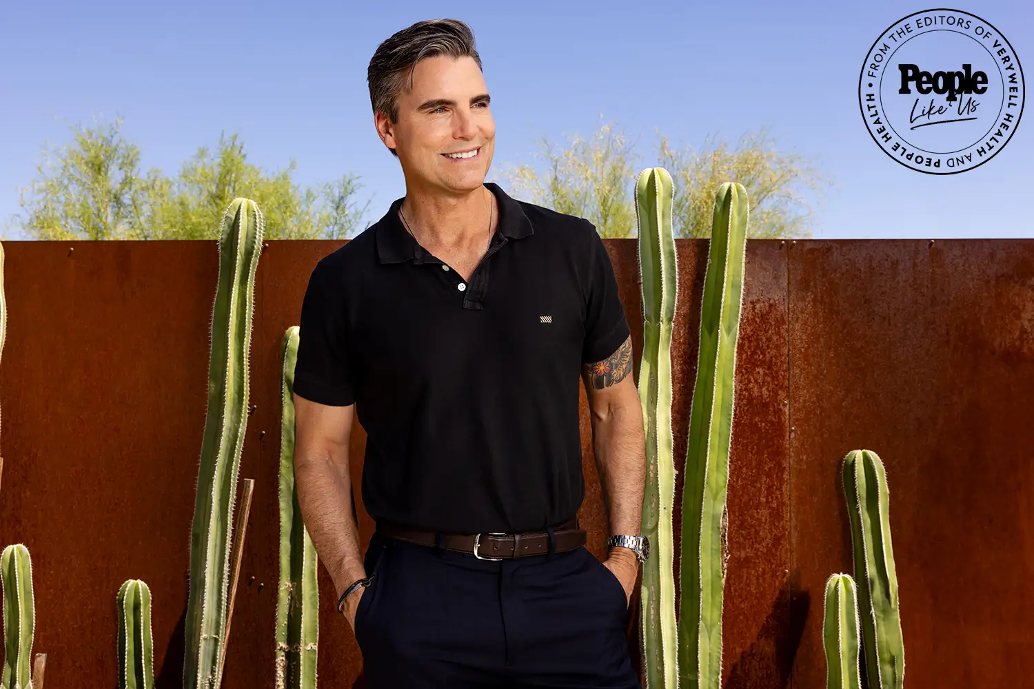 Actor Colin Egglesfield in black shirt stands by cactus in sunny setting Actor Colin Egglesfield in black shirt stands by cactus in sunny setting