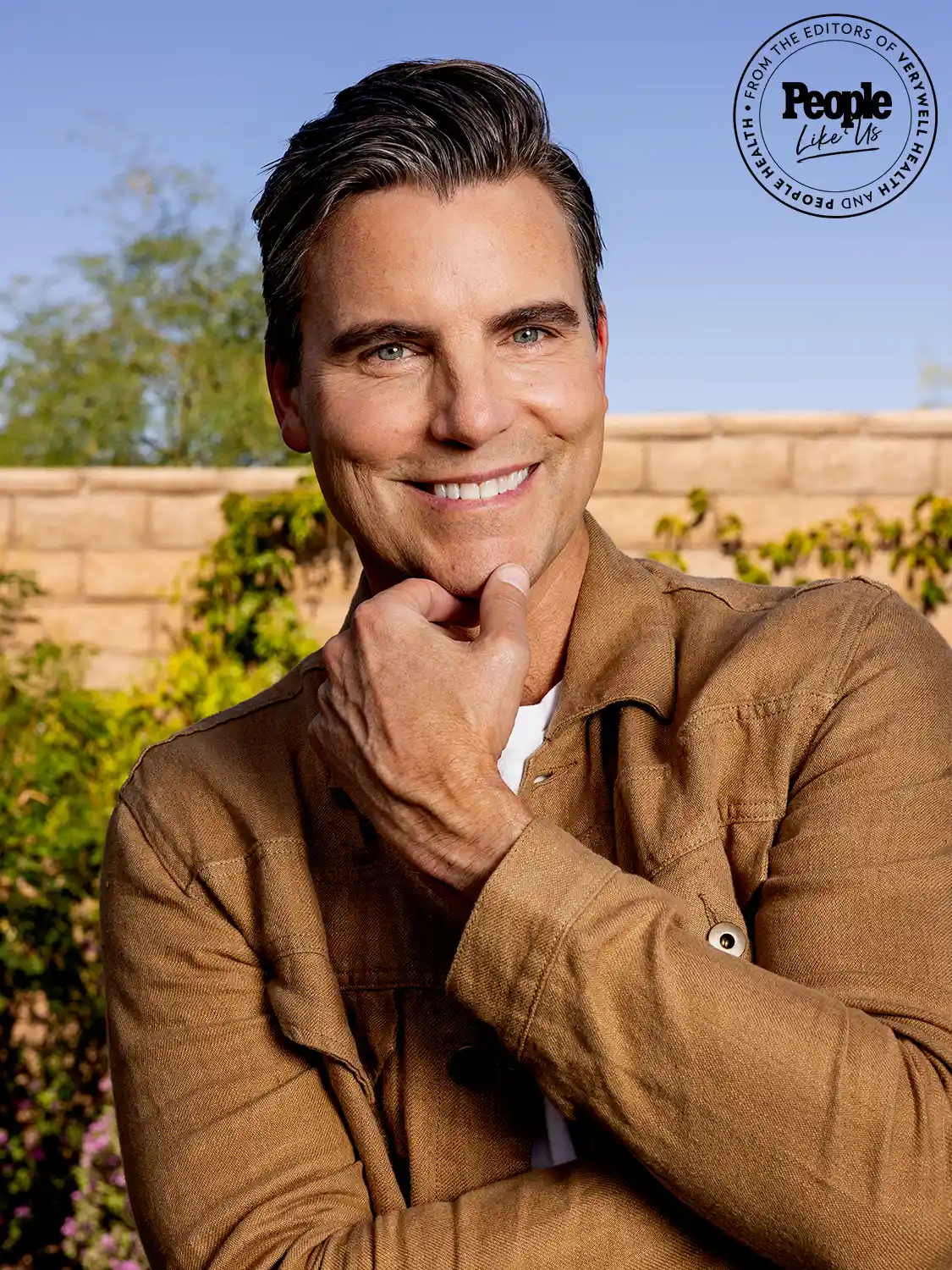 Actor Colin Egglesfield in tan jacket poses with hand on chin. Actor Colin Egglesfield in tan jacket poses with hand on chin