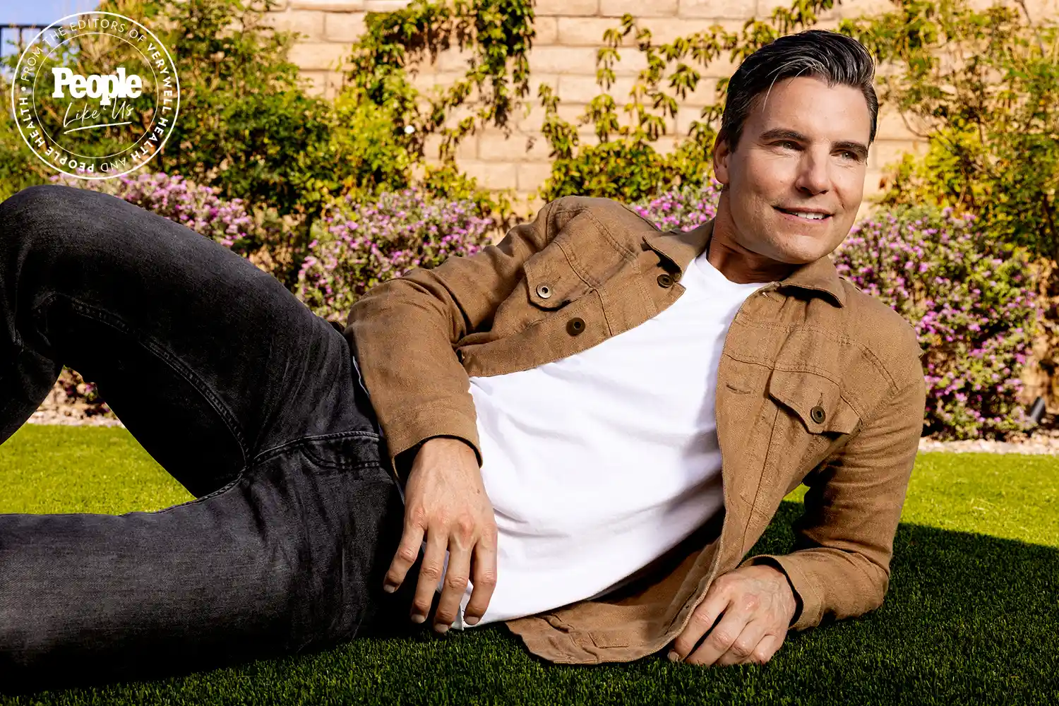 Hollywood Actor Colin Egglesfield in jacket lies back near flowers in garden Hollywood Actor Colin Egglesfield in jacket lies back near flowers in garden
