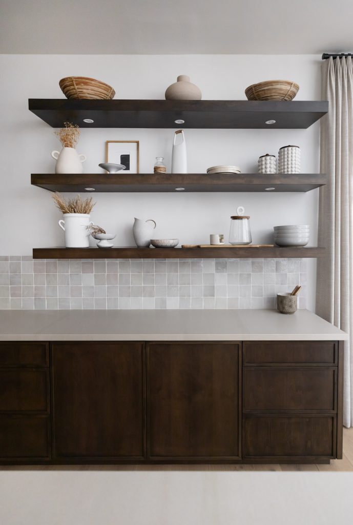 Dark wood open shelves with ceramic dishes and jars are mounted above a tiled backsplash and dark wood cabinets. — Living with Lolo.