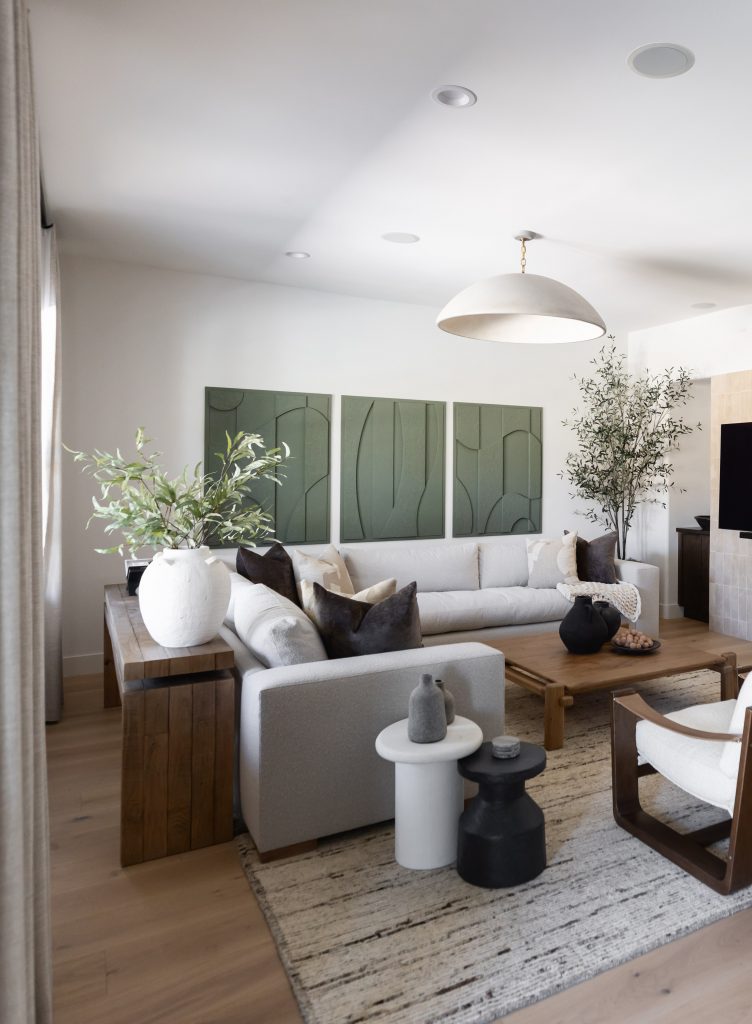 Modern living room with a white sofa, black and white accents, wooden coffee table, green wall art, and neutral rug—Living with Lolo.