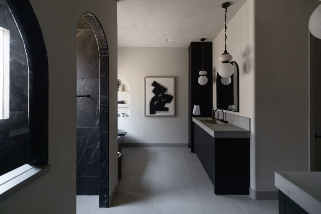 Bathroom with black and white decor, black tiled shower, double vanities, pendant lights, and abstract wall art. — Living with Lolo.