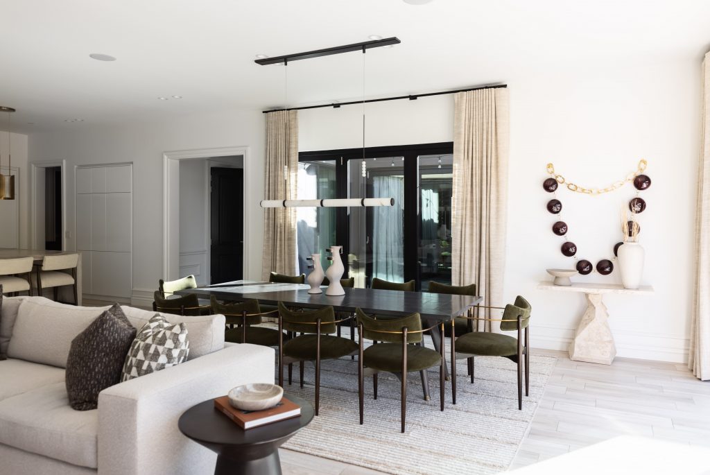 Dining area with a black table, green chairs, decorative vases, neutral walls, large windows, and contemporary wall art— Living with Lolo.