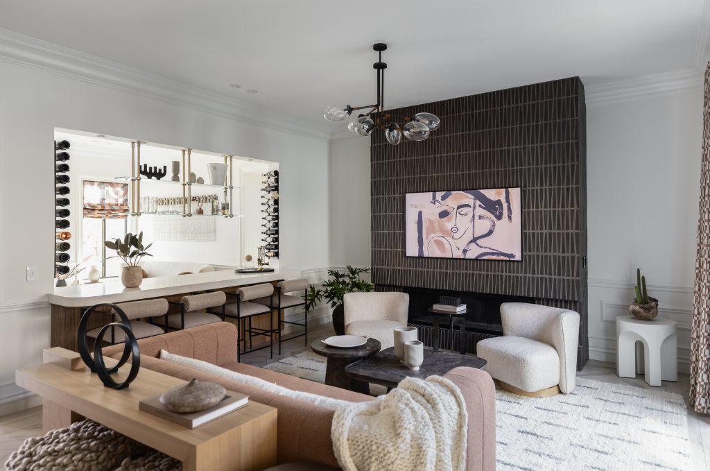 Modern living room with neutral-toned furniture, black tiled fireplace, abstract art, and an open kitchen with bar seating—Living with Lolo.