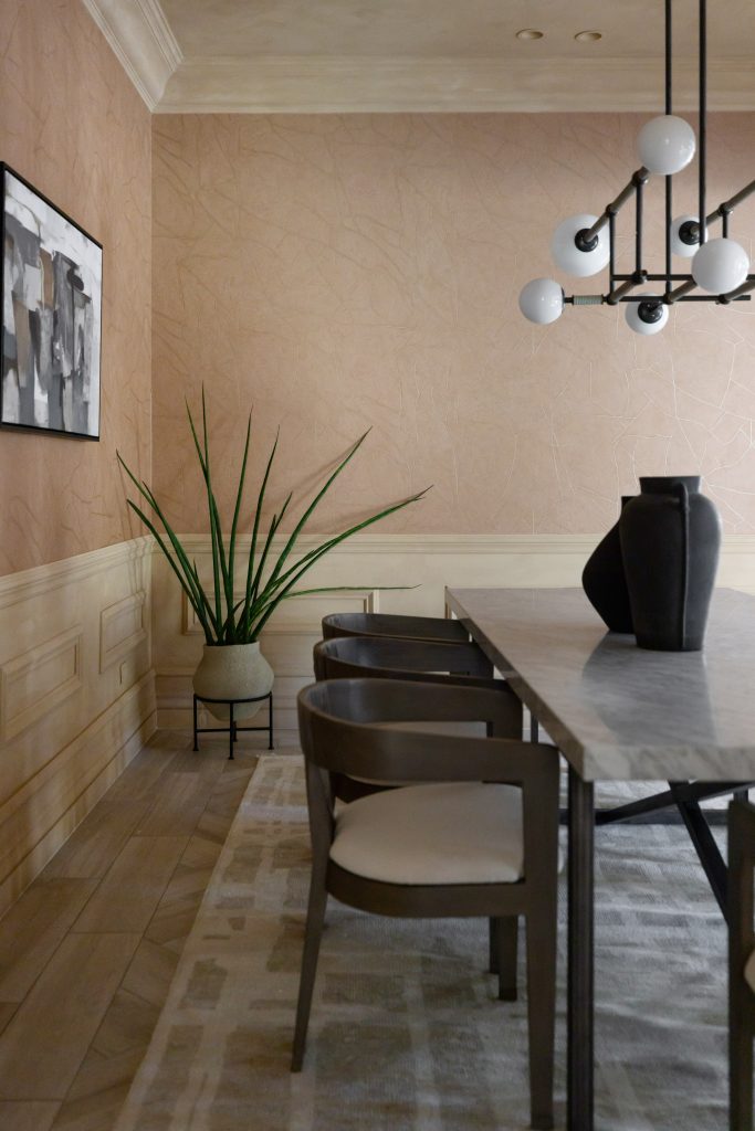 A dining room with a marble table, wooden chairs, a geometric chandelier, tall potted plant, and abstract wall art — Living with Lolo.