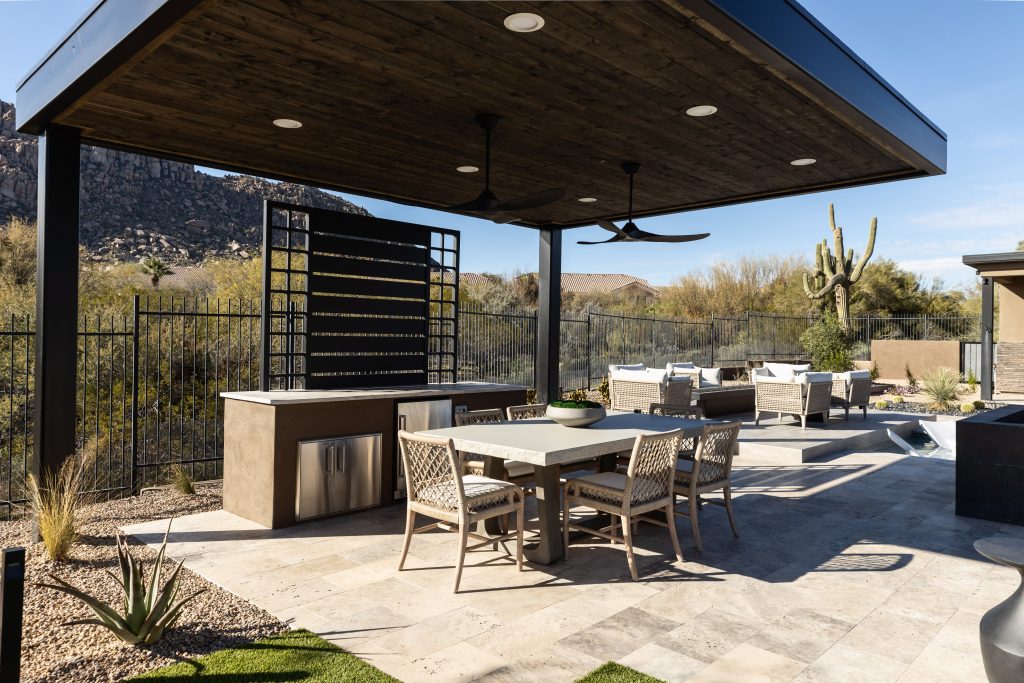 Modern outdoor patio featuring a covered dining area, grill station, lounge seating, and desert landscaping—Living with Lolo.