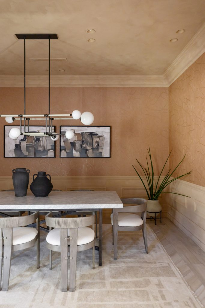 A dining room with a rectangular marble table, four chairs, black vases, abstract wall art, a potted plant, and a modern light fixture. — Living with Lolo.