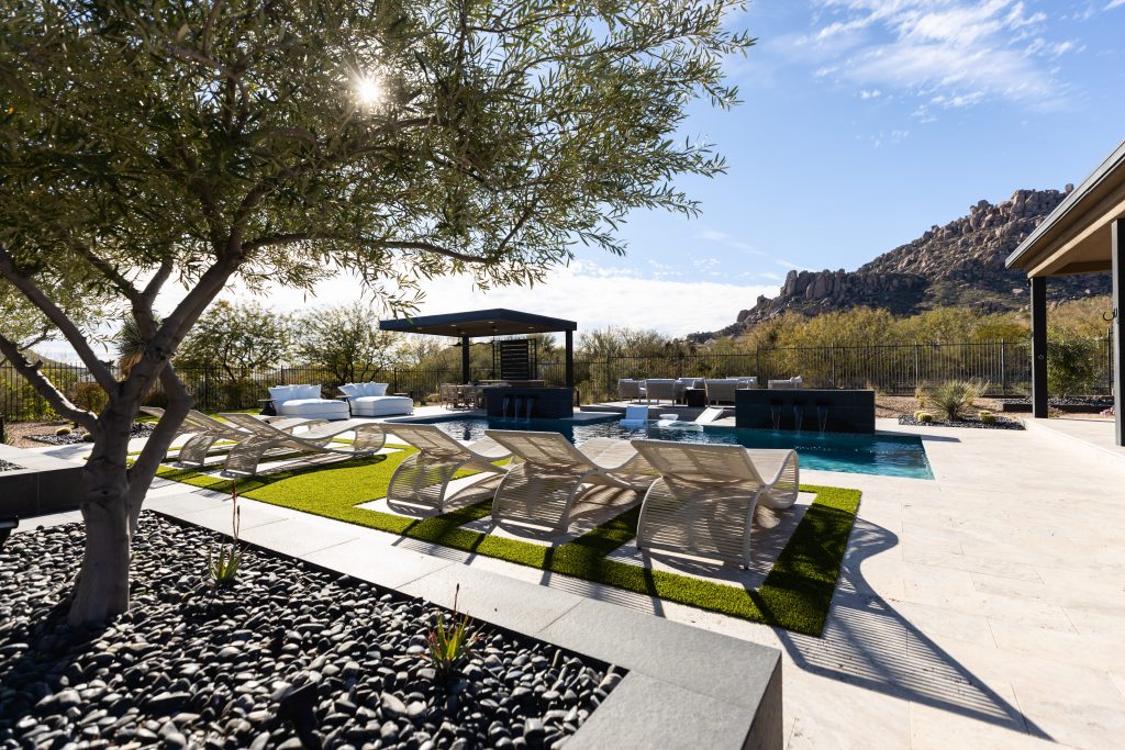 Modern backyard featuring lounge chairs, a small pool, shaded seating, and desert landscaping with mountains in the background—Living with Lolo.
