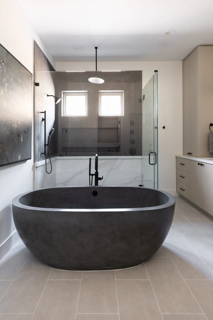 Modern bathroom featuring a freestanding black bathtub, glass shower enclosure, large wall art, and neutral-toned cabinetry — Living with Lolo.