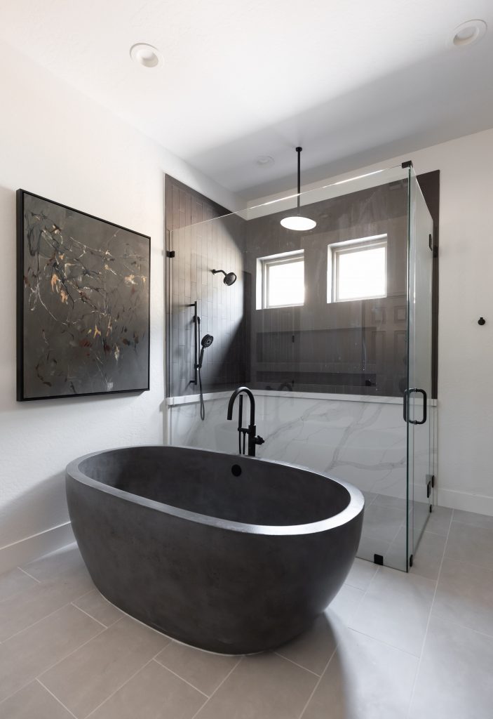 Modern bathroom featuring a black freestanding bathtub, glass shower enclosure, wall-mounted fixtures, and abstract wall art— Living with Lolo.