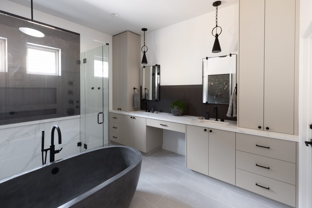 A modern bathroom with a black freestanding tub, glass shower, dual sinks, light cabinets, and pendant lighting—Living with Lolo.