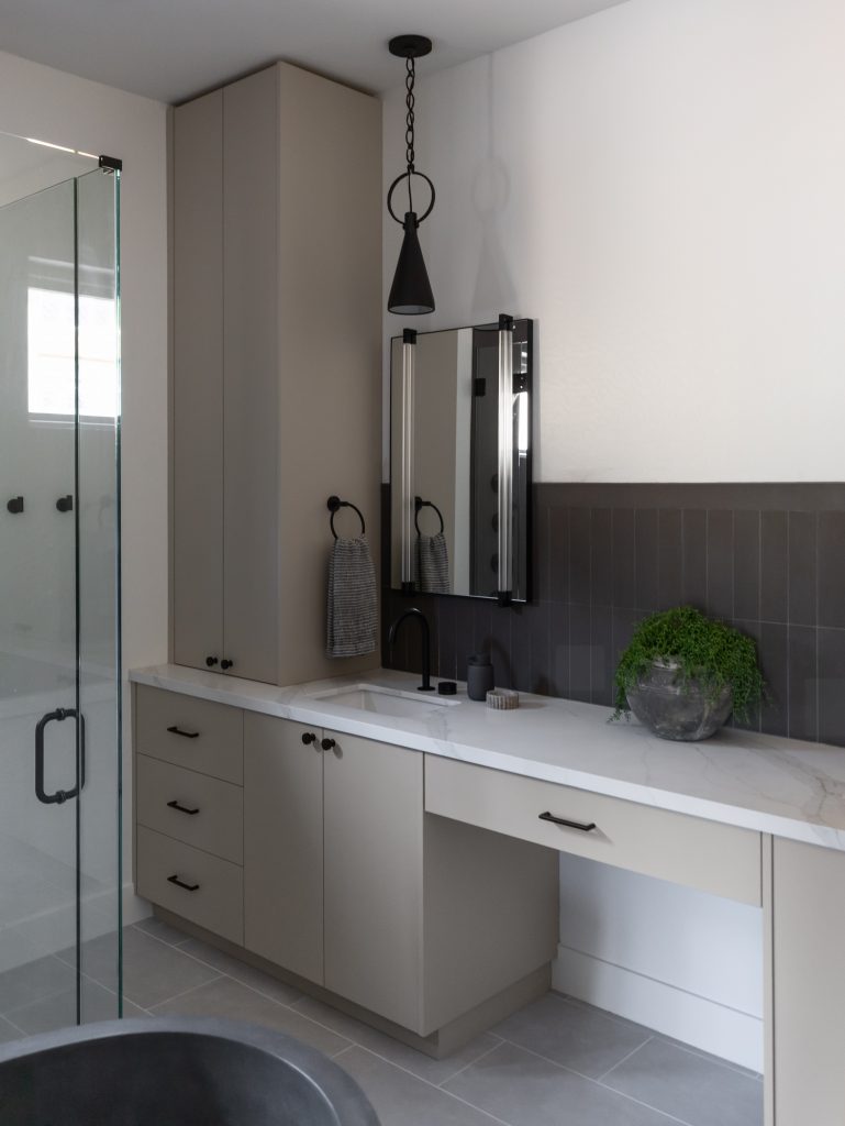 Modern bathroom with light gray cabinets, white countertop, black-framed mirror, dark fixtures, and a glass shower. — Living with Lolo.