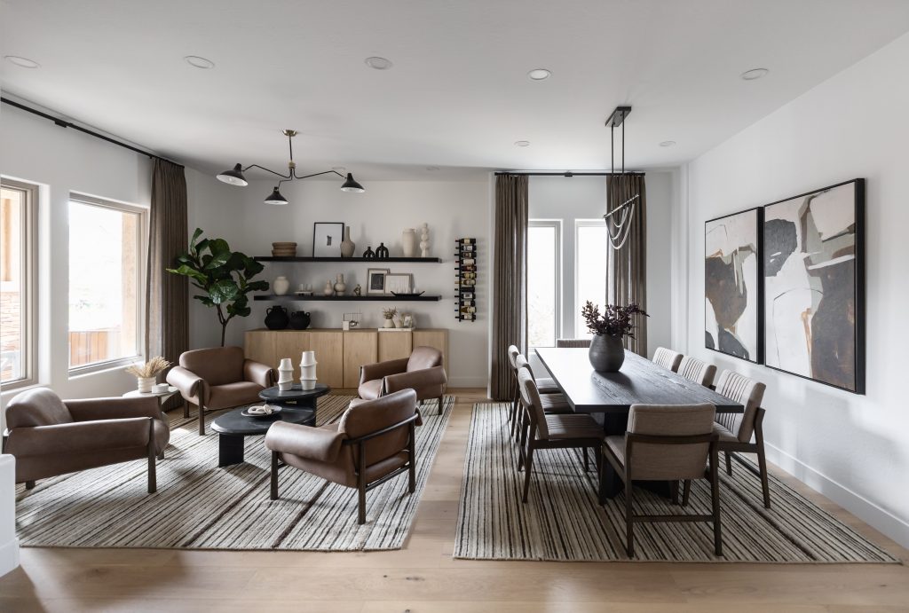 Open-concept living and dining room with neutral decor, leather chairs, black dining table, abstract art, and striped rugs on wood floors — Living with Lolo.