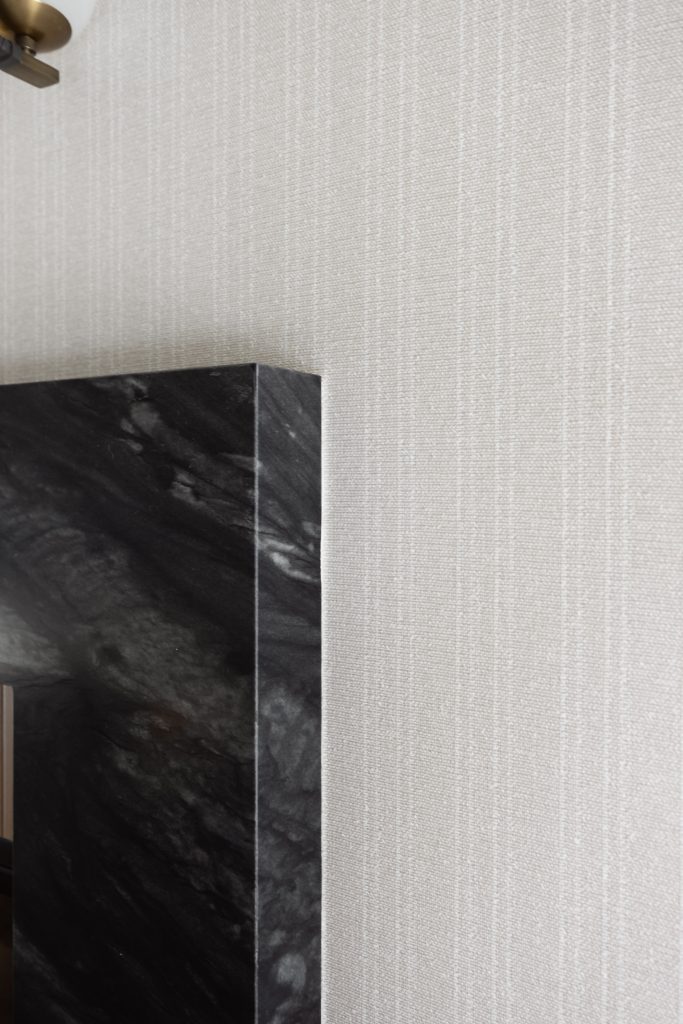 A polished black marble surface meets a beige textured wall with vertical lines—Living with Lolo.