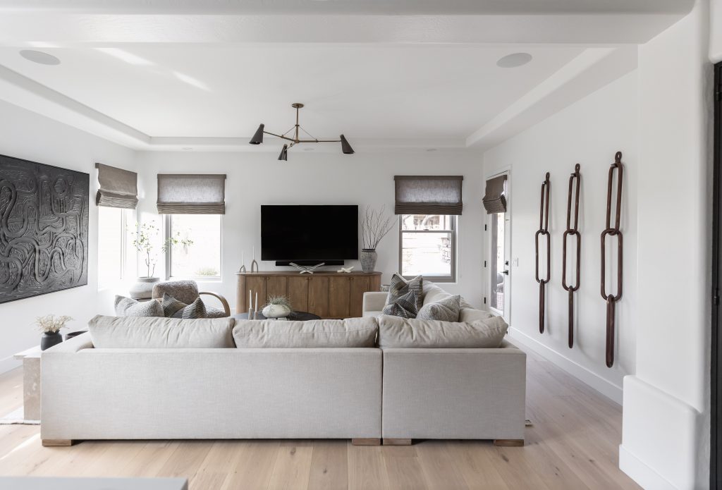 Modern living room featuring a light gray sectional, wall-mounted TV, wooden console, and three large decorative wall pieces—Living with Lolo.