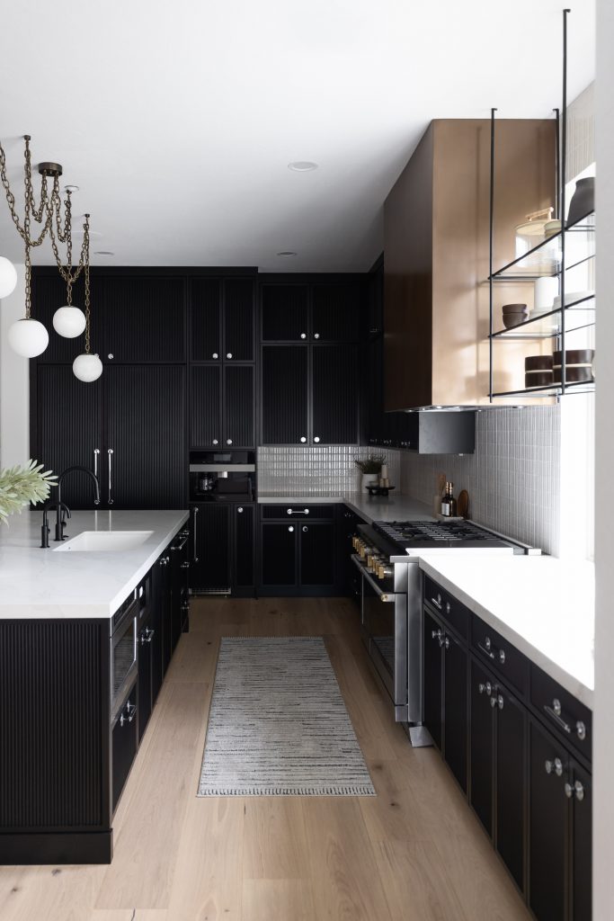 Black cabinets, white countertops, light wood floors, a bronze range hood, open shelves, and pendant lights above the island. — Living with Lolo.
