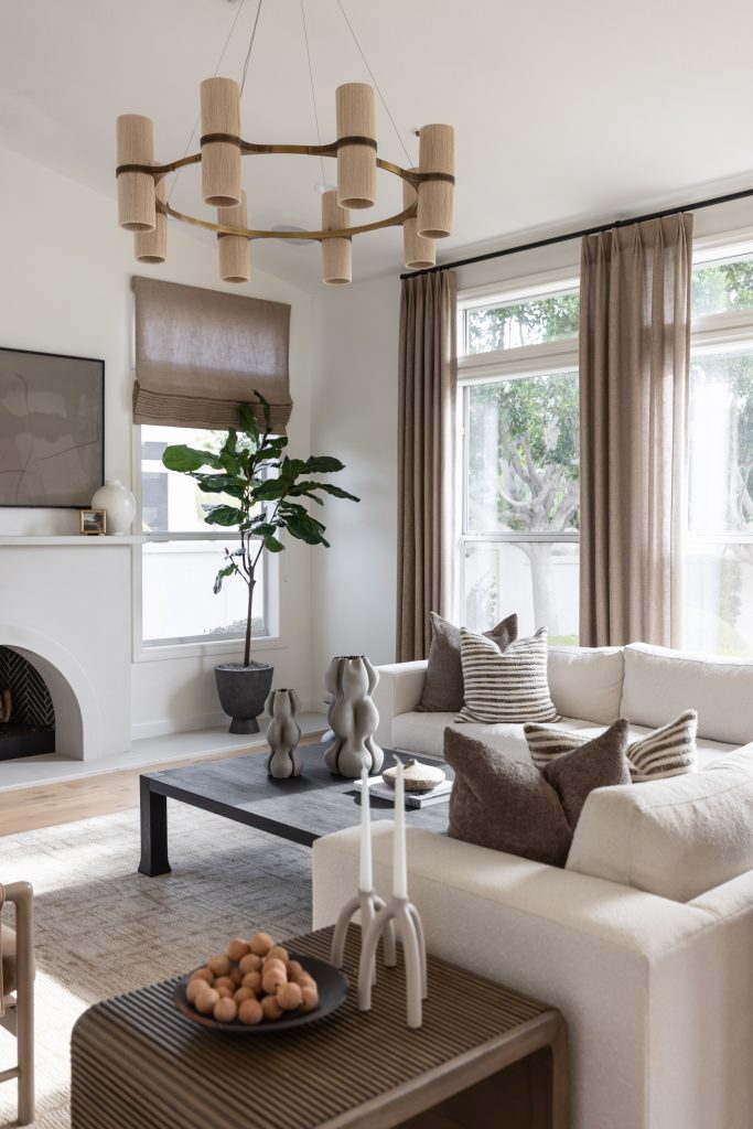 Modern living room with a white sectional sofa, beige curtains on large windows, a black coffee table, and a modern light fixture— Living with Lolo.
