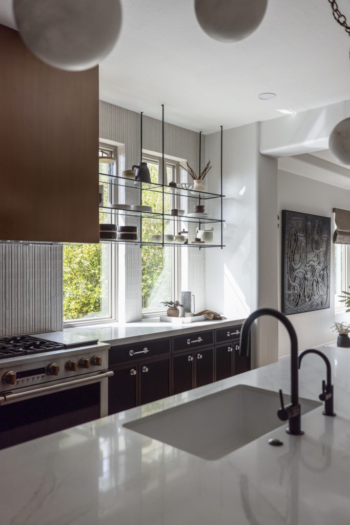 Modern kitchen with dark cabinets, marble countertop, built-in stove, open shelves with decor, and large windows—Living with Lolo.