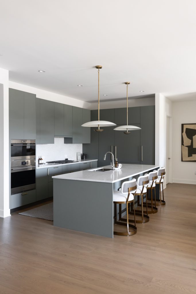 Modern kitchen with gray cabinets, white countertops, an island with four bar stools, pendant lights, and built-in appliances— Living with Lolo.
