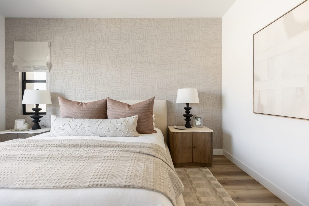 Modern bedroom featuring a patterned accent wall, neutral bedding, twin bedside tables with lamps, and abstract wall art— Living with Lolo.