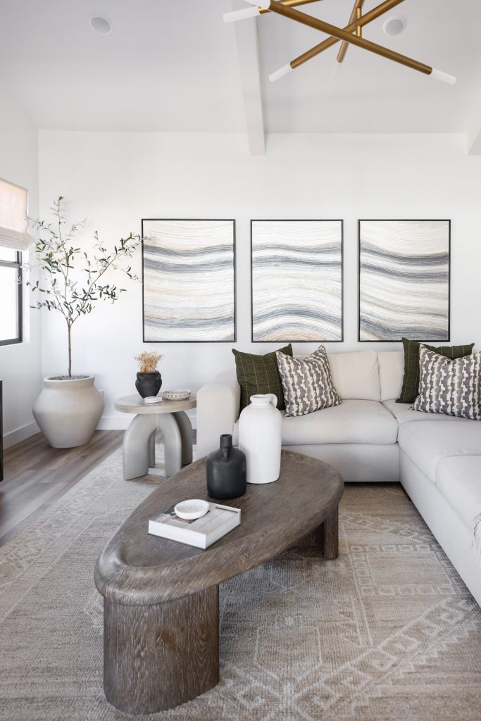 Modern living room featuring a beige sectional sofa, wooden coffee table, neutral artwork, potted plants, and a modern light fixture—Living with Lolo.