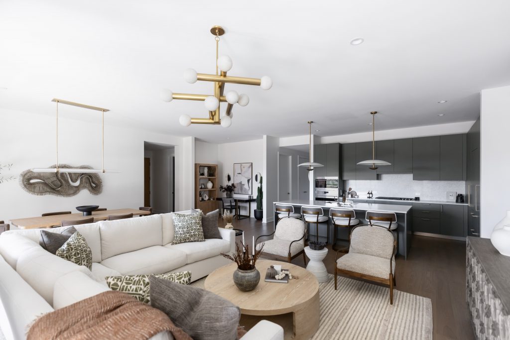 Open-concept living space with a white sectional, adjacent dining area, and kitchen featuring dark cabinets and pendant lights — Living with Lolo.