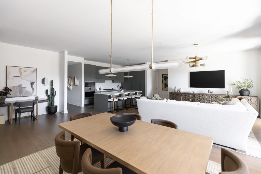 Open-plan space with a dining table and chairs, white sofa, kitchen island, modern lighting, art, and a cactus. — Living with Lolo.