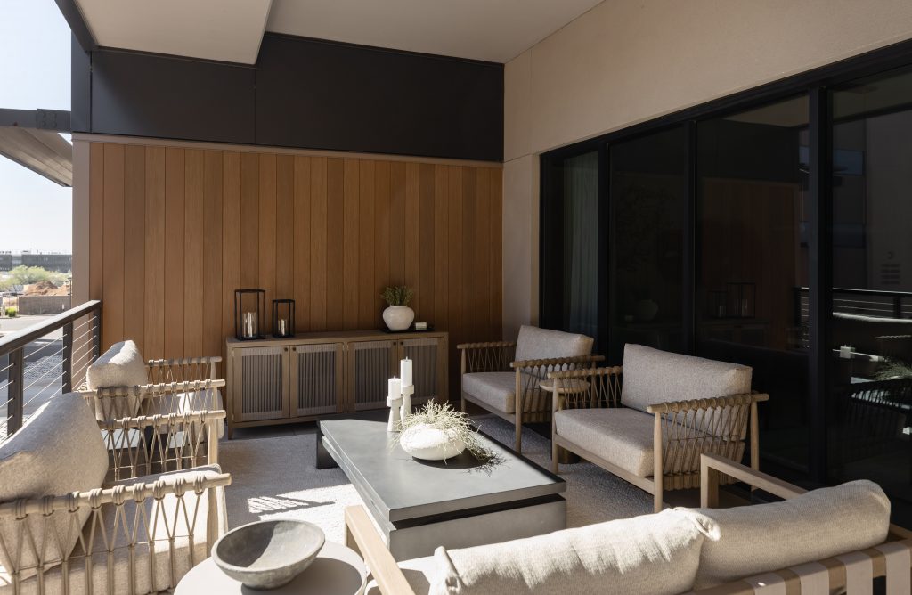 A modern outdoor patio with cushioned chairs, a sofa, coffee table, decorative accents, wooden wall cabinets, and potted plants. — Living with Lolo.