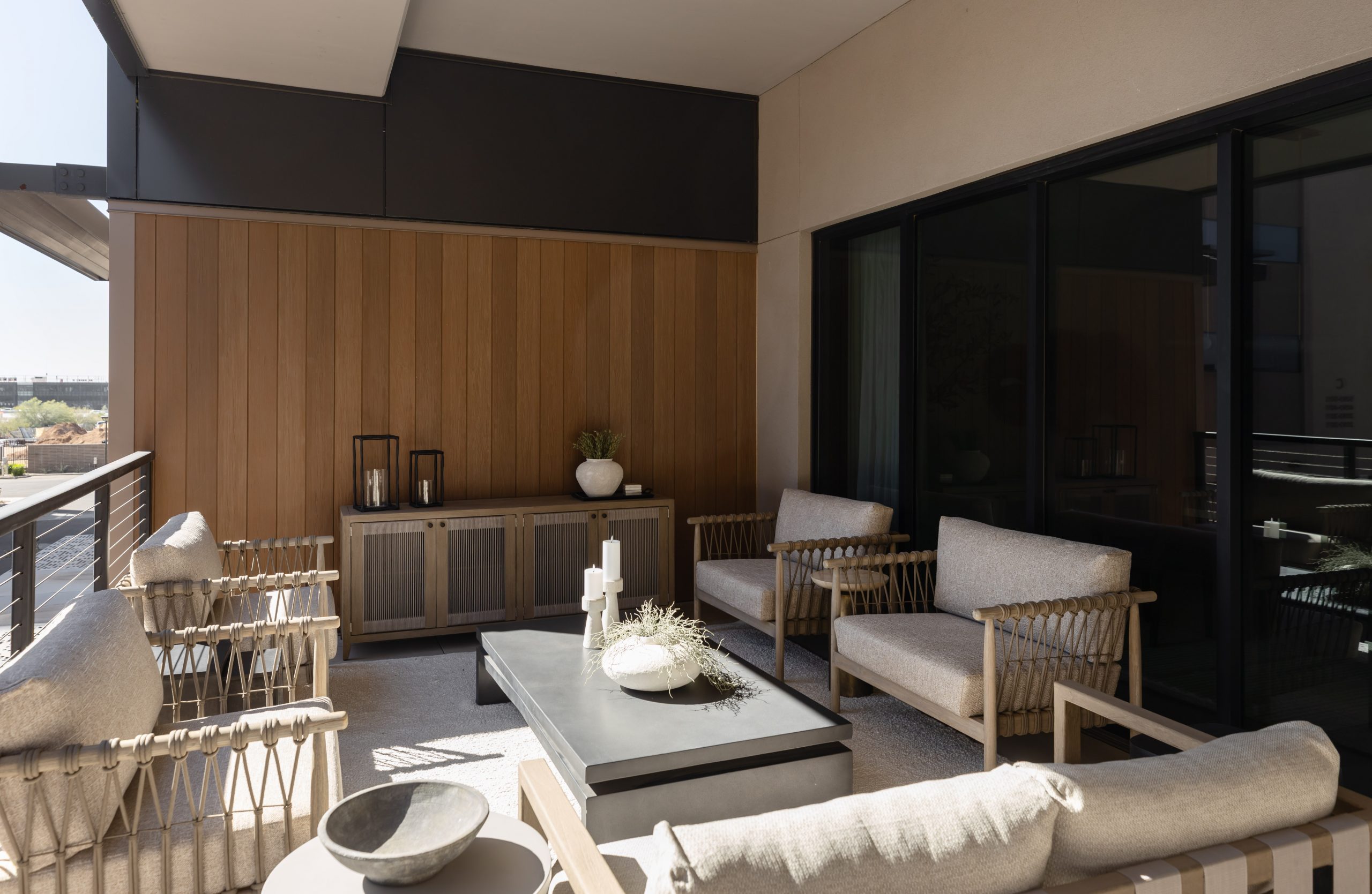 A modern outdoor patio with cushioned chairs, a sofa, coffee table, decorative accents, wooden wall cabinets, and potted plants. — Living with Lolo.