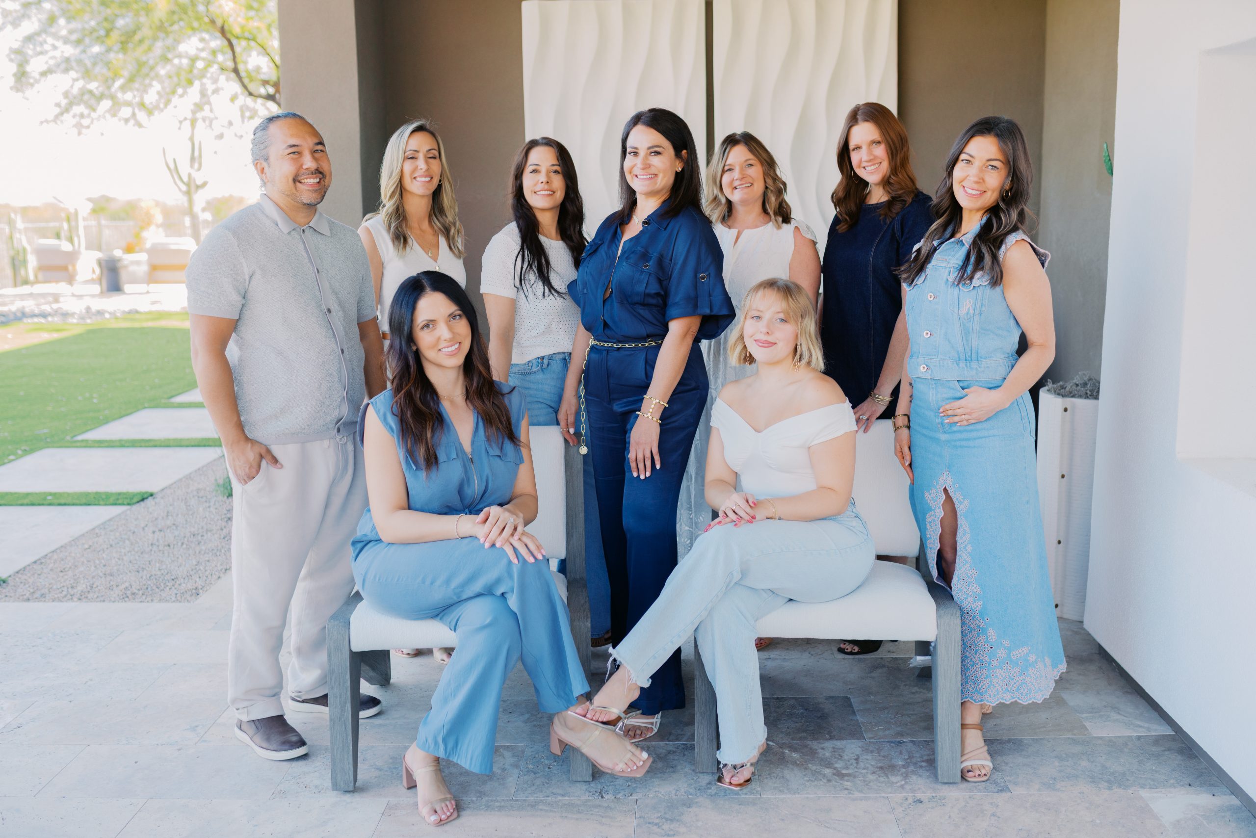 Ten adults gather on a modern outdoor patio with two women seated and the others standing, showcasing the patio design — Living with Lolo.