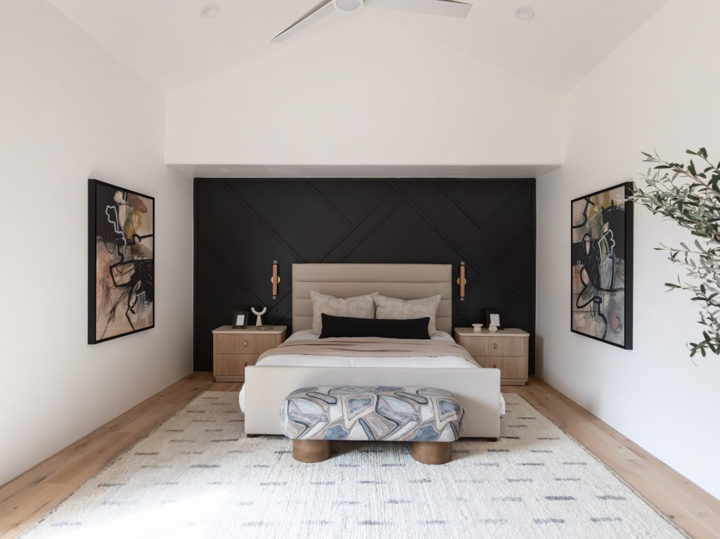 A modern bedroom features a beige bed, abstract artwork on the walls, and a patterned bench at the foot of the bed, with neutral decor. — Living with Lolo.
